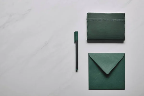 Enveloppe verte et carnet avec stylo sur fond de marbre blanc — Stock Photo