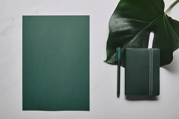 Green stationery set and monstera leaf on white marble background — Stock Photo