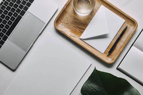 Pose plate avec modèle d'affaires avec papier, enveloppe et ordinateur portable sur fond de marbre blanc — Photo de stock