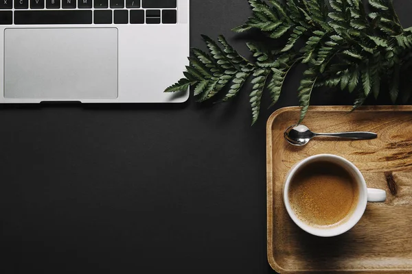 Tazza di caffè nero dal computer portatile su sfondo nero — Foto stock