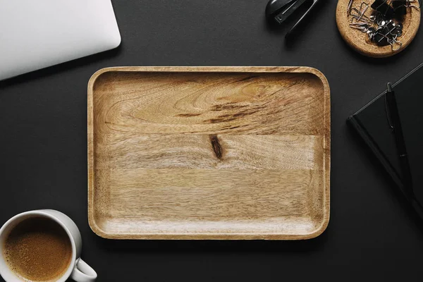 Empty wooden board on black background with laptop and stationery — Stock Photo