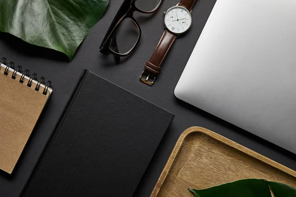 Flat lay com Notebook e laptop com óculos e assistir em fundo preto — Fotografia de Stock