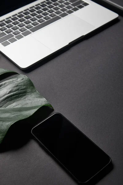 Smartphone avec écran blanc par ordinateur portable sur fond noir — Photo de stock