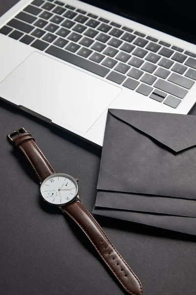 Black envelops and watch by laptop on black background — Stock Photo