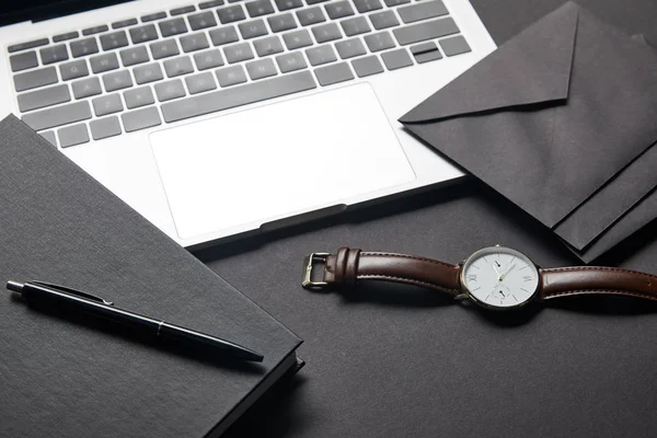 Laptop with black envelope and watch on black background — Stock Photo