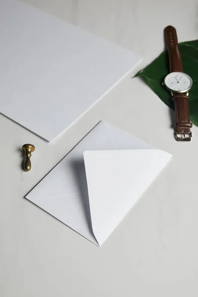 White envelope with brown watch on white marble background — Stock Photo