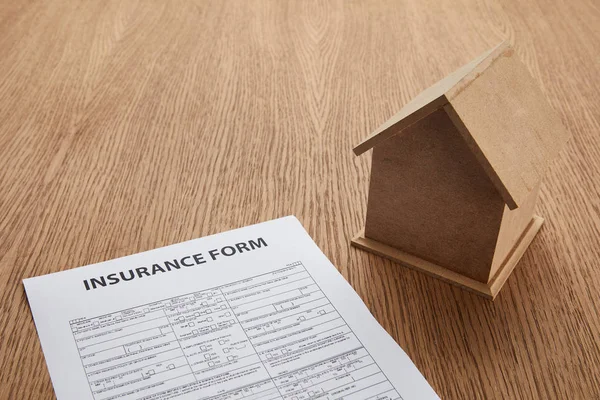 Close-up view of insurance form and small house model on wooden table with copy space — Stock Photo