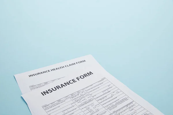 Visão de perto da forma de seguro e formulário de pedido de seguro de saúde isolado no azul — Fotografia de Stock