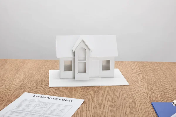 Vue rapprochée du formulaire d'assurance et du modèle de petite maison sur une table en bois — Photo de stock