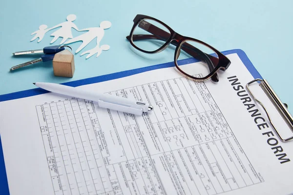 Formulario de seguro, anteojos, bolígrafo, familia de corte de papel y llaves aisladas en azul - foto de stock