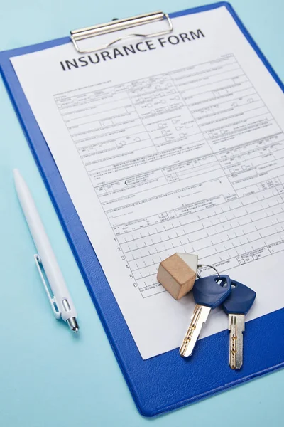 Vista de cerca del formulario de seguro, bolígrafo y llaves aislados en azul - foto de stock