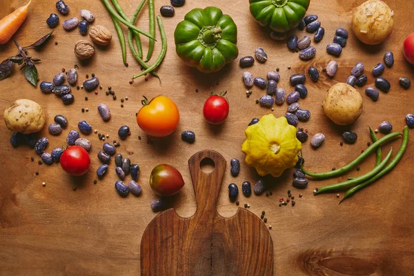 Feijões e legumes crus com tábua de corte em mesa de madeira — Fotografia de Stock