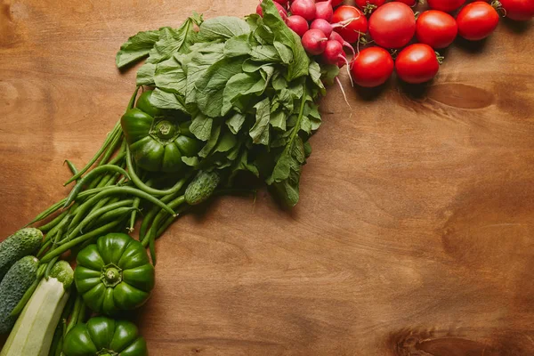 Verduras verdes y rojas de verano sobre mesa de madera - foto de stock