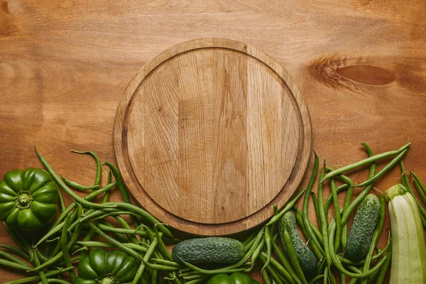 Tábua de corte com legumes verdes na mesa de madeira — Fotografia de Stock