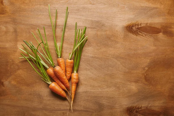 Bunch of raw carrots on wooden table — Stock Photo