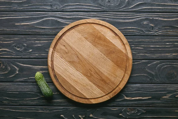 Tagliere e cetriolo su tavolo di legno scuro — Foto stock