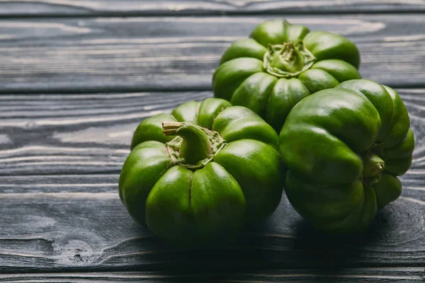 Bunch of green bell peppers on dark wooden table — Stock Photo