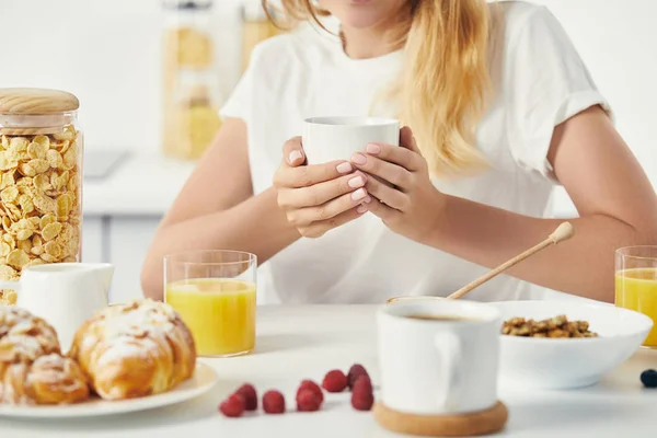Частичный вид женщины с чашкой кофе, завтракающей дома — стоковое фото