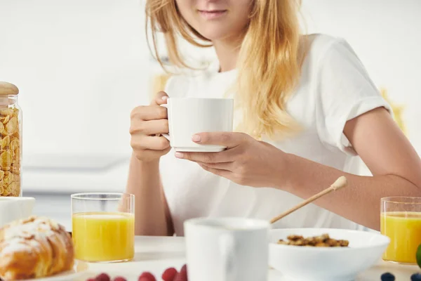Vista parcial de la mujer con taza de café desayunando en casa - foto de stock