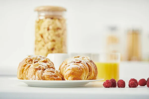 Close up view of freshly baked croissants and raspberries for breakfast on white surface — Stock Photo