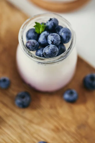 Close up view of yogurt with fresh blueberries for breakfast on wooden cutting board — Stock Photo