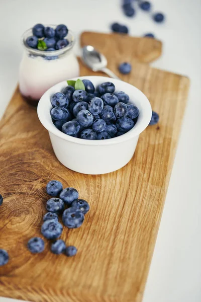 Vue rapprochée des bleuets frais et du yaourt pour le petit déjeuner sur planche à découper en bois — Photo de stock