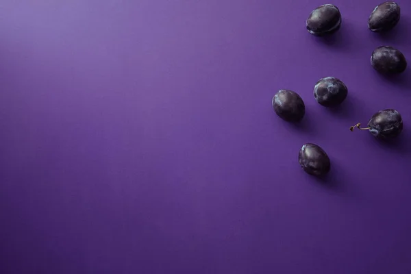 Vista superior de ameixas maduras na superfície violeta — Fotografia de Stock