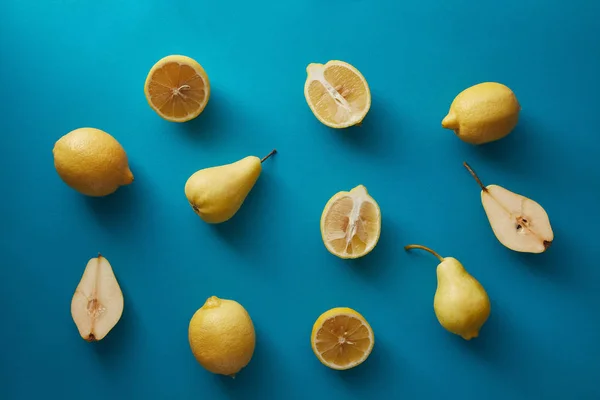 Vista elevada de peras maduras y limones sobre la superficie azul - foto de stock