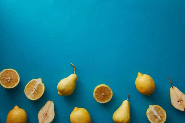 Вид сверху груш и лимонов на голубую поверхность — стоковое фото