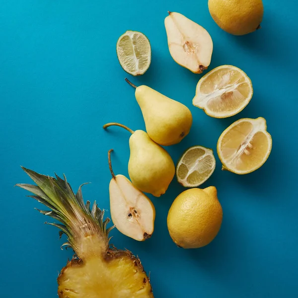 Vista dall'alto di ananas maturo, pere e limoni su superficie blu — Foto stock