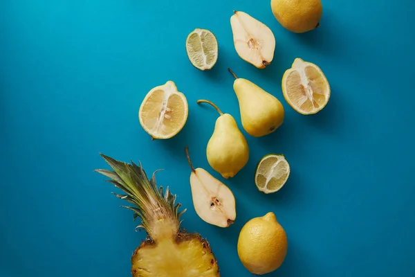 Vue surélevée de l'ananas, des poires et des citrons sur la surface bleue — Photo de stock