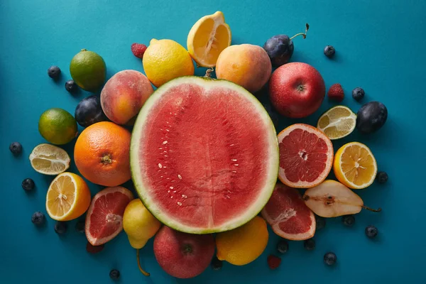 Vista superior de la sandía y otras frutas diferentes en la superficie azul - foto de stock