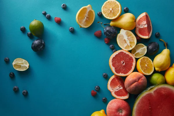 Vue surélevée des fruits mûrs appétissants et des baies sur la surface bleue — Photo de stock