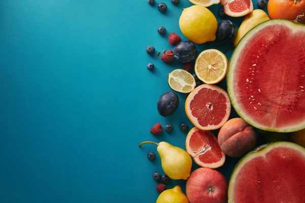 Vista dall'alto di pompelmi, limoni e bacche sulla superficie blu — Foto stock