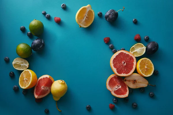 Top view of organic ripe fruits and berries on blue surface — Stock Photo