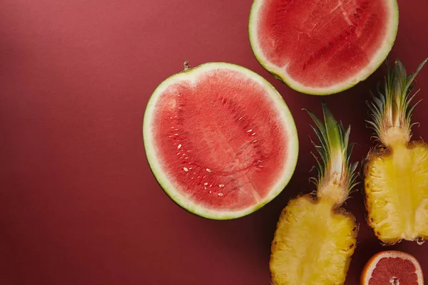 Vue de dessus de pastèque et d'ananas coupés sur la surface rouge — Photo de stock