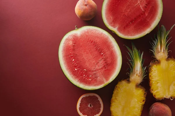 Vista superior de frutas cortadas en la superficie roja - foto de stock