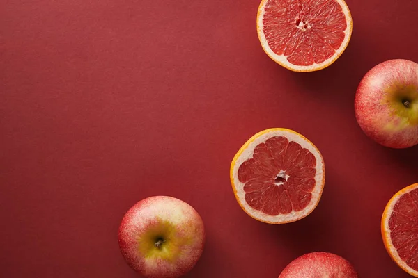 Vue de dessus des pamplemousses et des pommes sur la surface rouge — Photo de stock