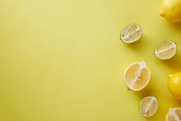 Vue de dessus des citrons et des citrons verts sur la surface jaune — Photo de stock