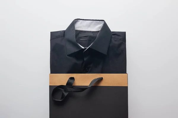 Вид зверху на нову чорну сорочку в сумці для покупок ізольовано на білому — стокове фото