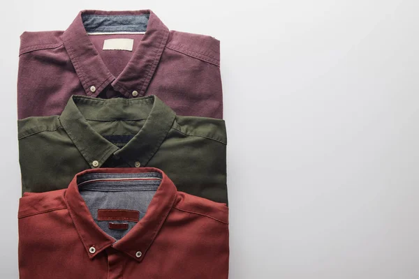 Leigos planos de três camisas coloridas isoladas em branco — Fotografia de Stock