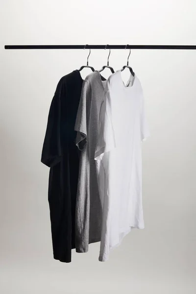 Camisas negras, grises y blancas en perchas aisladas en blanco - foto de stock