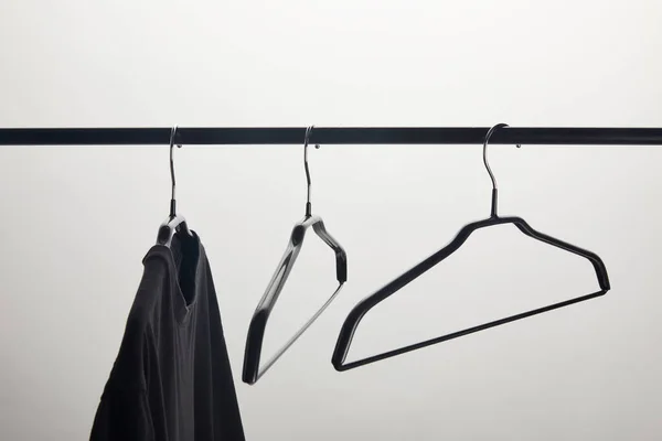 Black shirt and empty hangers on stand isolated on white — Stock Photo