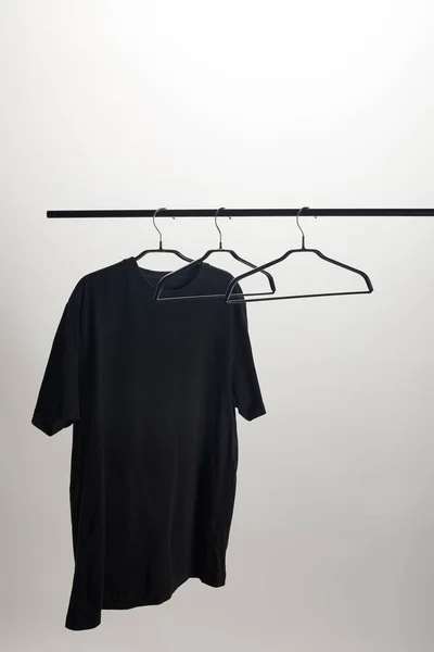 Uma camisa preta e cabides vazios no suporte isolado no branco — Fotografia de Stock