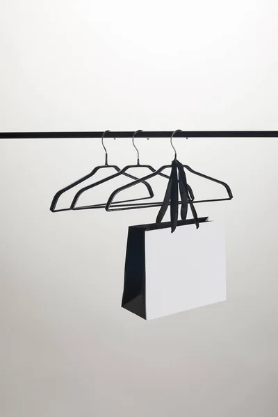 Einkaufstasche und leere Kleiderbügel am Stand isoliert auf weiß — Stockfoto