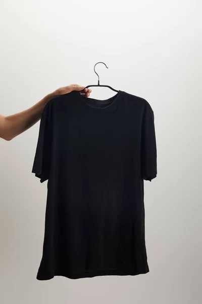 Cropped image of woman holding hanger with black shirt isolated on white — Stock Photo