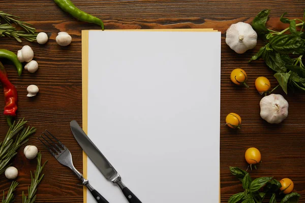 Vue du dessus de la carte blanche, des couverts et des légumes frais sur la surface en bois — Photo de stock