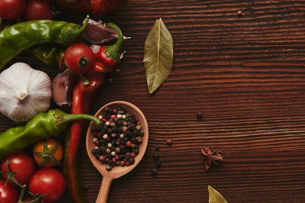 Vue de dessus de cuillère en bois avec des grains de poivre et des légumes frais sur la table — Photo de stock