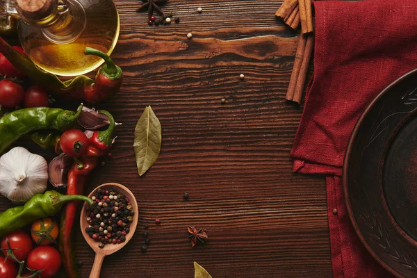 Top view of red tablecloth, round plate, spices and vegetables on wooden surface — Stock Photo