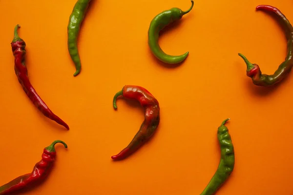 Top view of fresh green and red chili peppers on orange background — Stock Photo